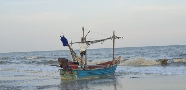 Fishing boat on beach against sky