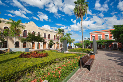 Plants by historic building against blue sky