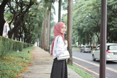 Portrait of young woman standing against trees