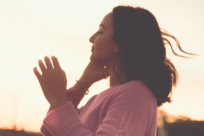 Side view of girl standing against clear sky at sunset