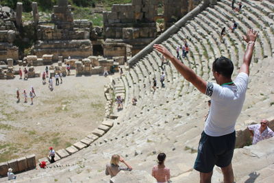 Rear view of man with arms outstretched standing at amphitheater
