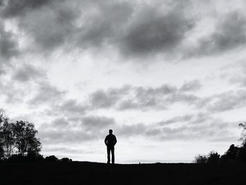 Silhouette of man standing against cloudy sky