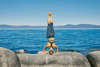 Young woman practicing yoga on lake tahoe in northern california.