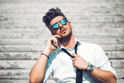 Young man wearing sunglasses standing against wall