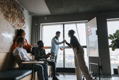 Business colleagues giving high-five in meeting at office