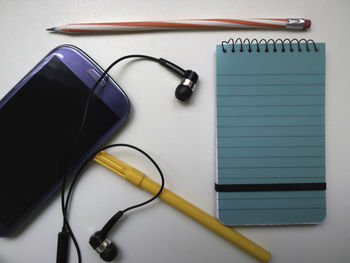 Close-up of mobile phone and pens on white background