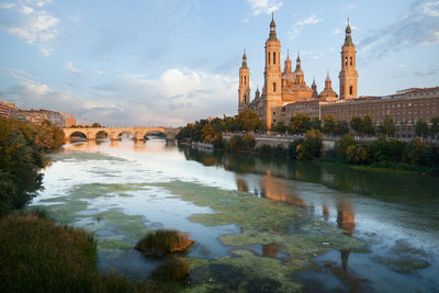 The basilica of the pilar, in zaragoza, reflected in the ebro river at sunset