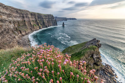 Scenic view of sea by cliff against sky