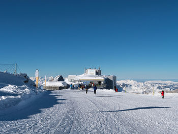 People on snowcapped mountain against clear blue sky