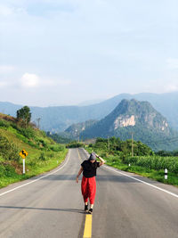 Full length of woman walking on road against sky