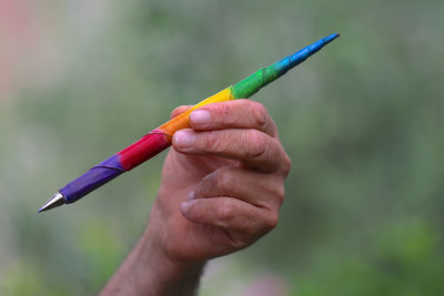 Close-up of hand holding multi colored pen