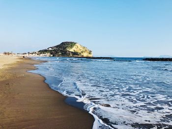 Scenic view of beach against clear blue sky