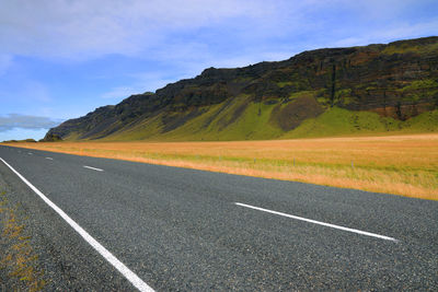 Road leading towards mountains against sky