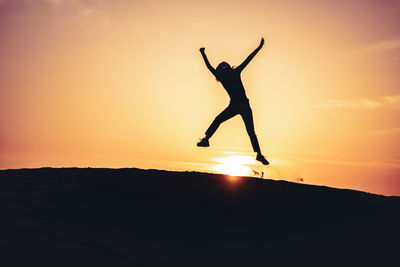 Silhouette man jumping against sky during sunset