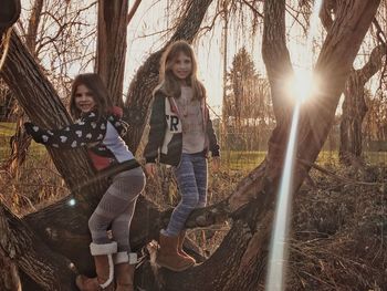 Portrait of happy friends standing on tree at park