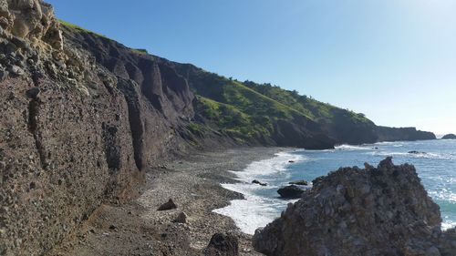 Rock formations by sea against clear sky