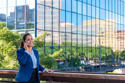 Full length of woman using mobile phone while standing on bridge