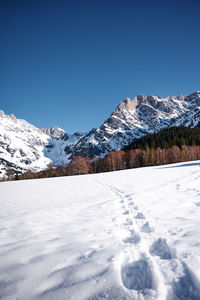 Scenic view of snowcapped mountains against clear blue sky