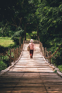 Rear view of woman walking on footbridge