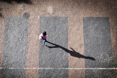 High angle view of woman walking with shadow on footpath