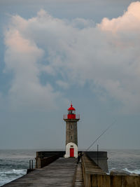 Lighthouse by sea against sky