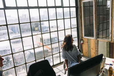 Young businesswoman sitting on chair against window in board room at creative workplace