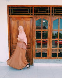 Portrait of woman standing against door