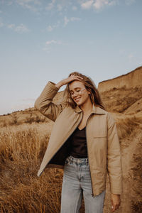 Young woman standing by plants against sky