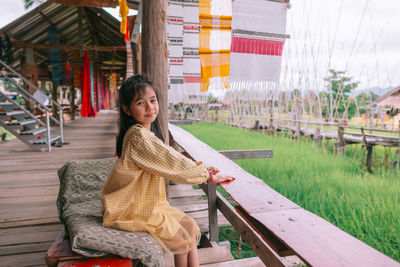 Portrait of young woman sitting on railing