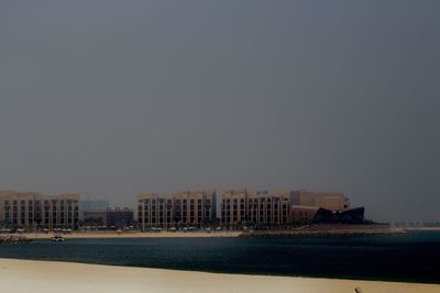 Buildings by sea against clear sky