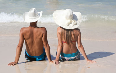 Rear view of couple sitting on beach