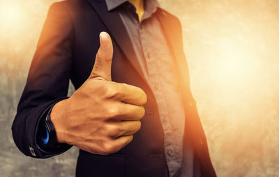 Midsection of businessman showing thumbs up