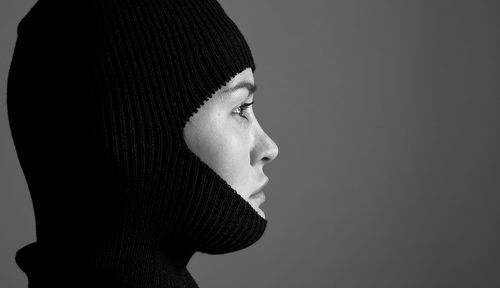 Side view of serious woman wearing knit hat against gray background