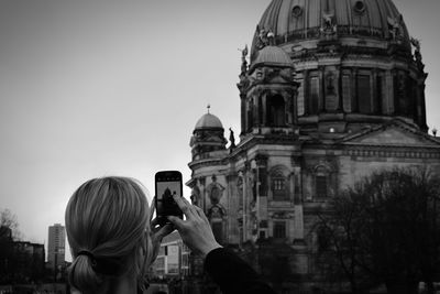 Rear view of woman photographing berlin cathedral in mobile phone