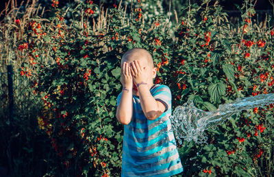 Portrait of boy standing against plants