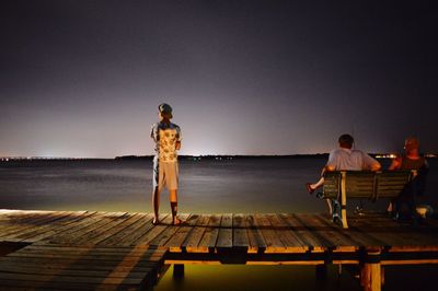 Rear view of people on pier at night