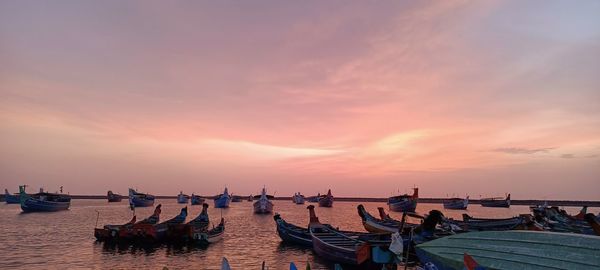 Boats moored at harbor during sunset