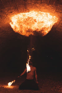 Young man with fire staff juggling in dark tunnel