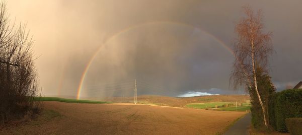 Panoramic shot of rainbow over land against sky