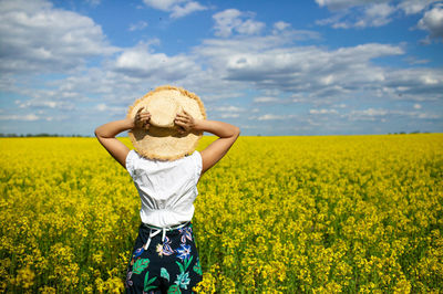 Happy girl in hat enjoying in summer flower field