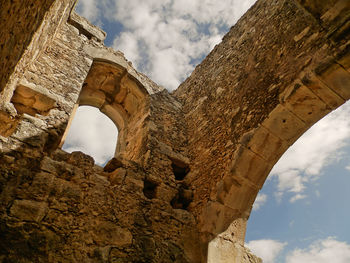 Low angle view of old ruin building against cloudy sky