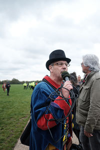 Men with people in background against sky