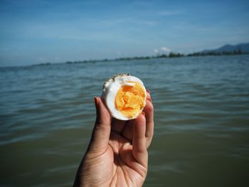 Close-up of hand holding ice cream against lake