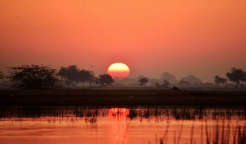 Scenic view of lake against orange sky