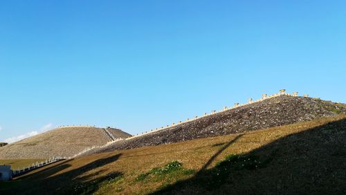 Road leading towards mountain against clear blue sky