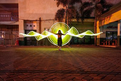 Full length of woman standing against illuminated building at night