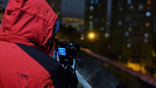 Rear view of man photographing illuminated city at night