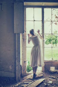 Side view of woman standing against wall