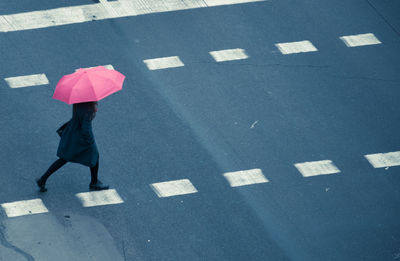 High angle view of woman under umbrella walking on road