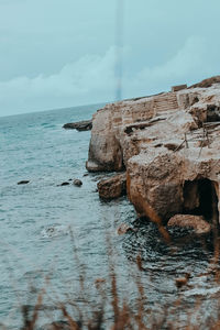 Rock formations on sea shore against sky